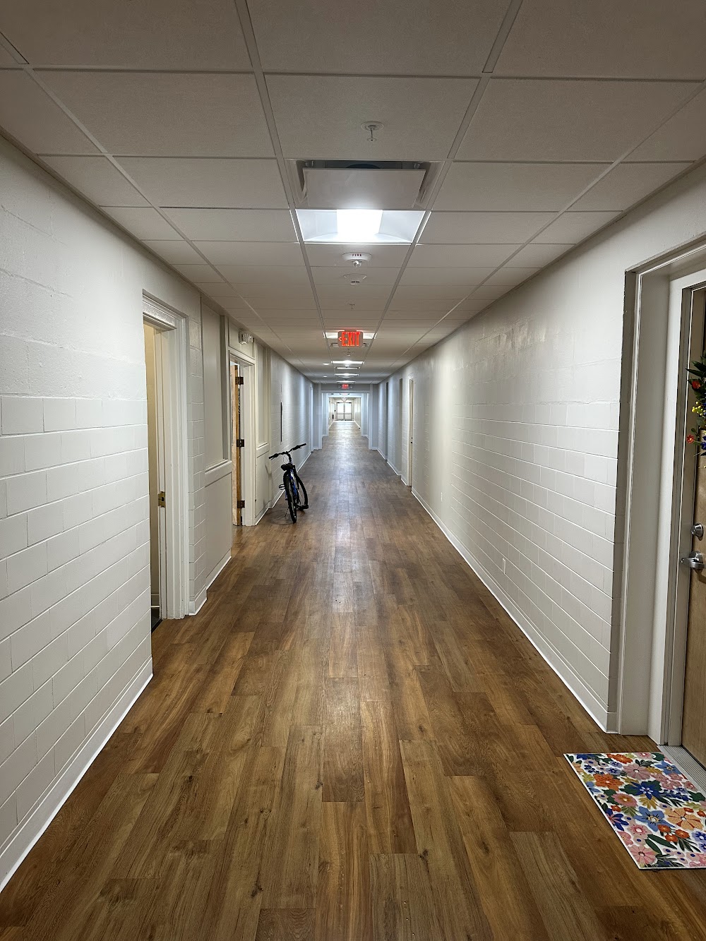 Long finished corridor with white walls and warm wood-look flooring