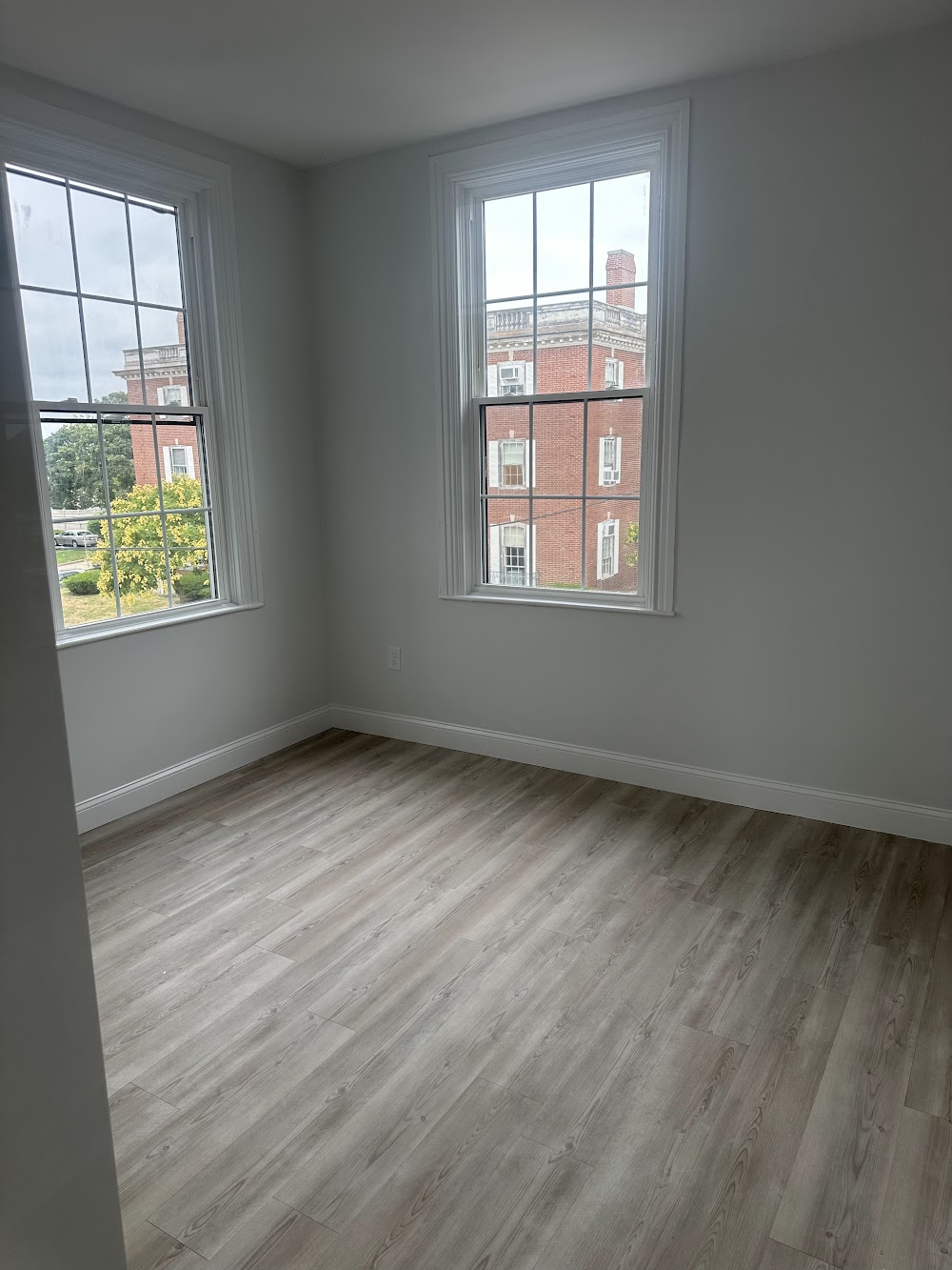Bright room with two tall windows and light wood-look flooring
